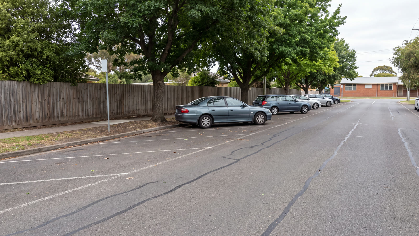 Quiet outer-metropolitan school corridor with a civic survey vehicle, marked kerb space and an abstract review tablet