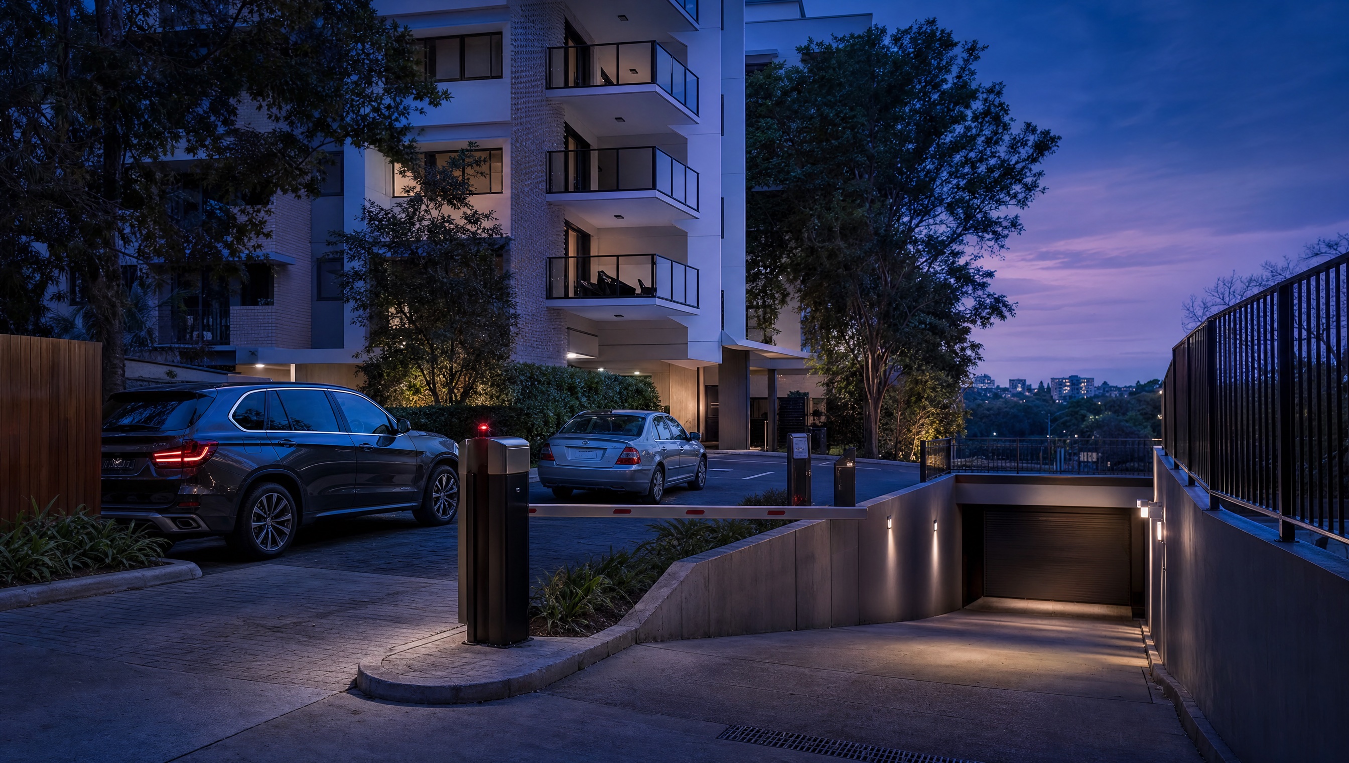 Residential building driveway and basement garage ramp with vehicle access controls at dusk