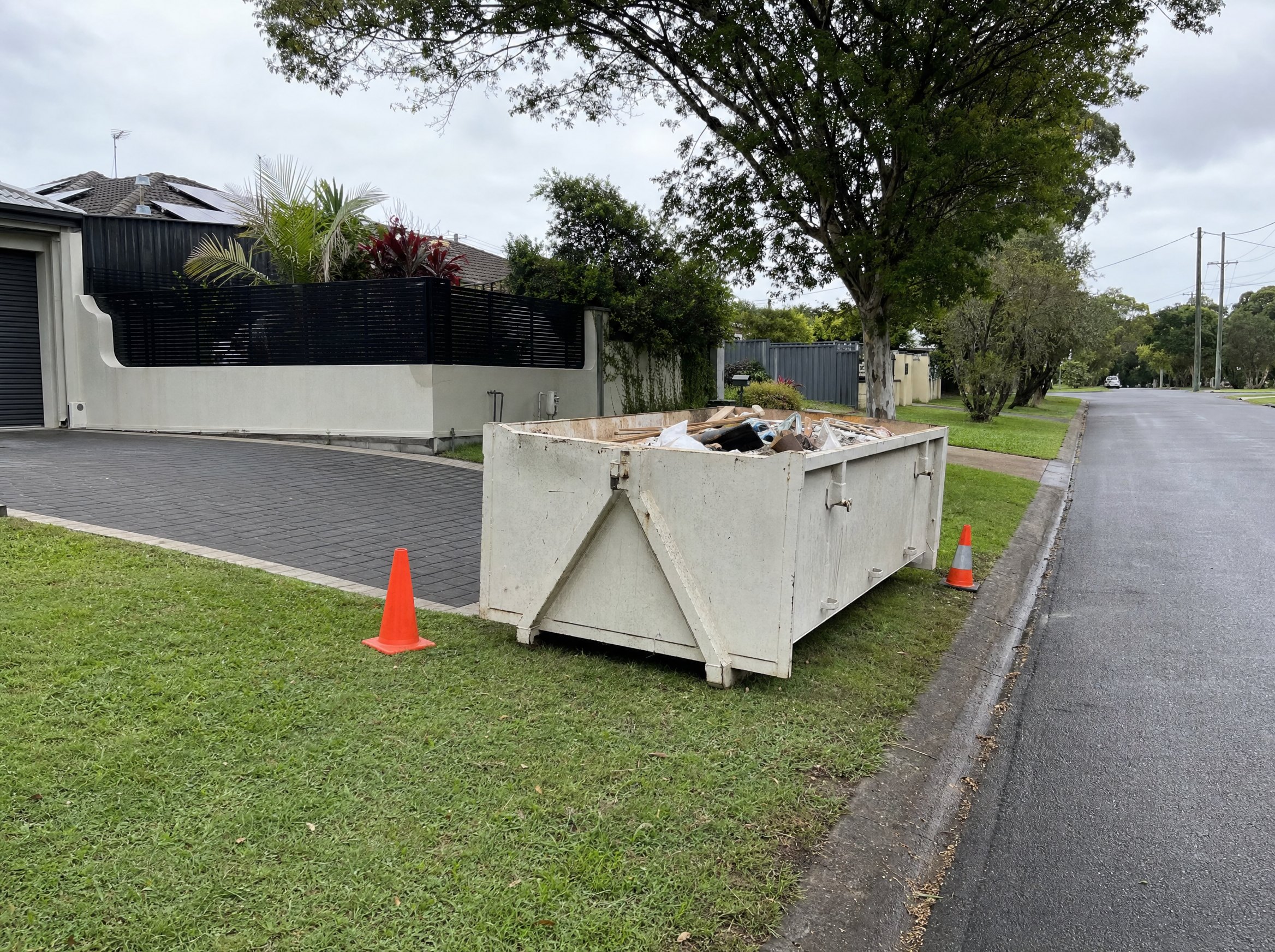 Skip bin placed on a suburban street verge with safety cone context